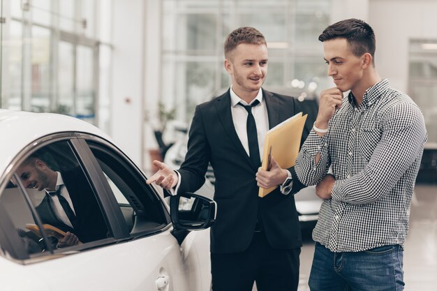 Vendedor explicando os detalhes de um carro a um cliente em concessionária