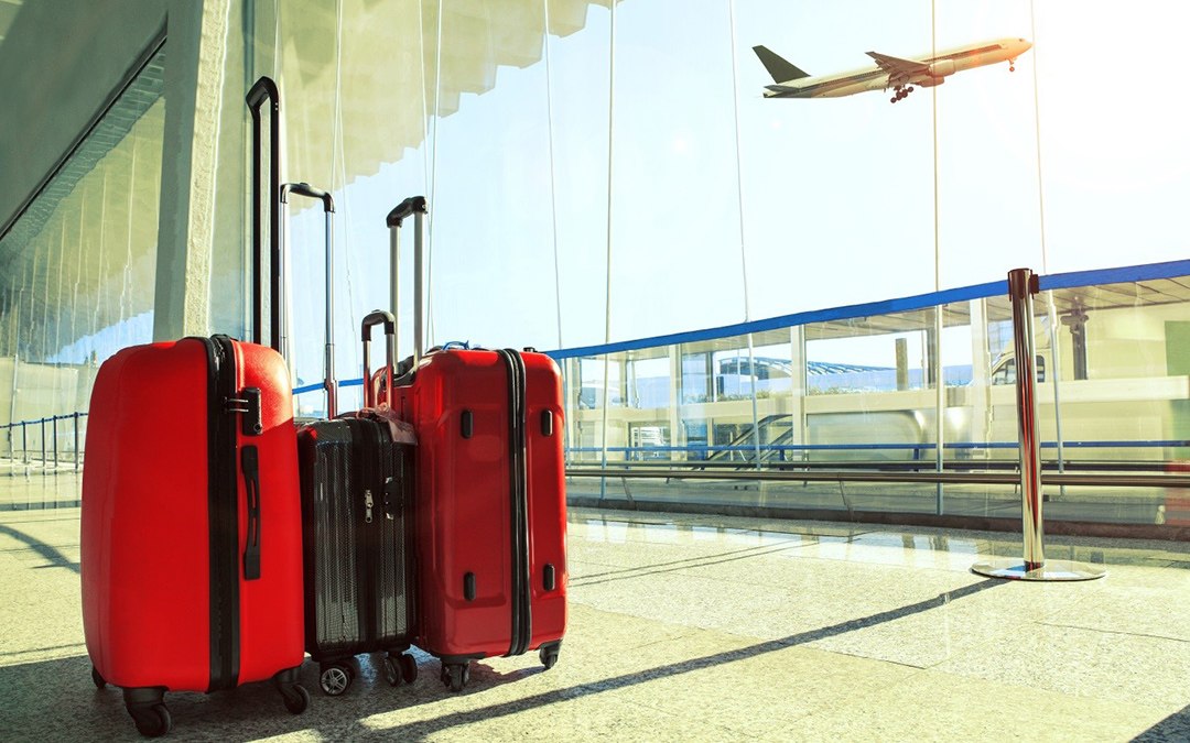 Malas em sala de embarque com avião decolando ao fundo